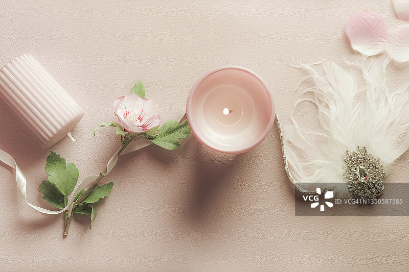 粉色背景上的淡粉色蜡烛、芙蓉花和羽毛饰品女性美妆背景图片素材