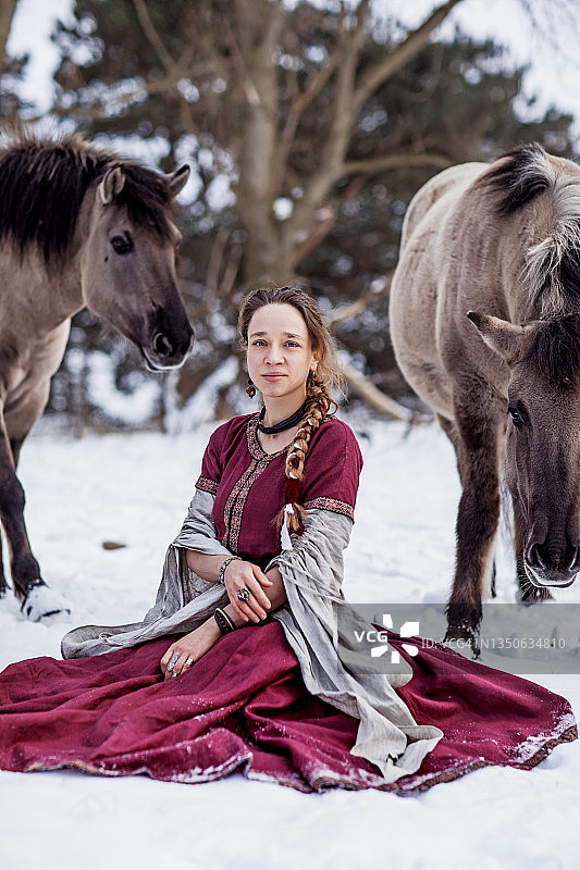 雪林中与马匹在一起的漂亮金发女性维京幻想战士女王图片素材