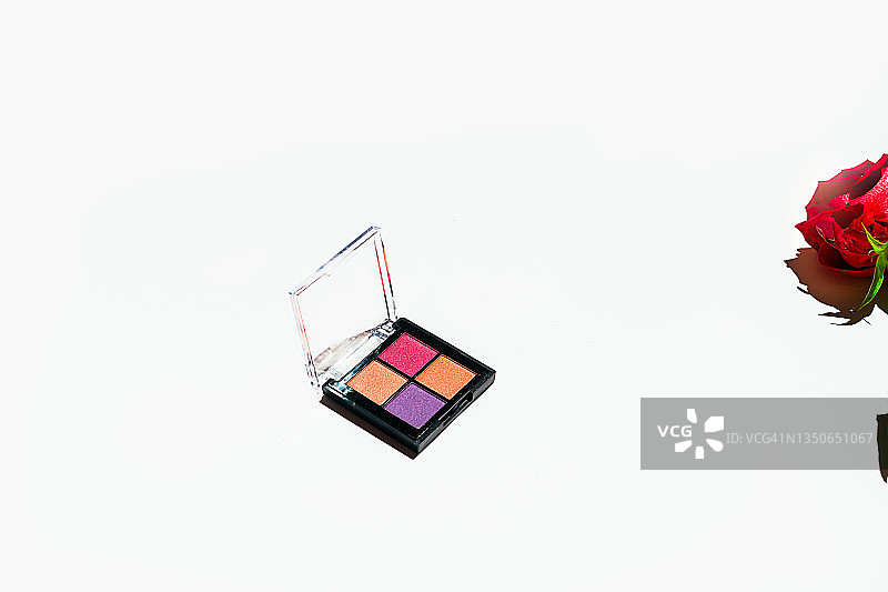 时尚多色眼影和红色玫瑰花与绿色叶子在白色背景上图片素材