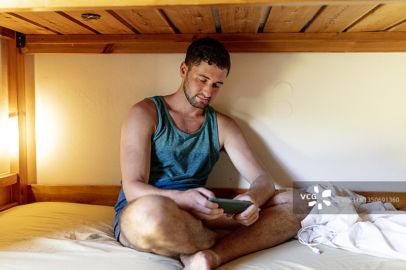 在宿舍式青年旅社使用手机的年轻旅行者图片素材