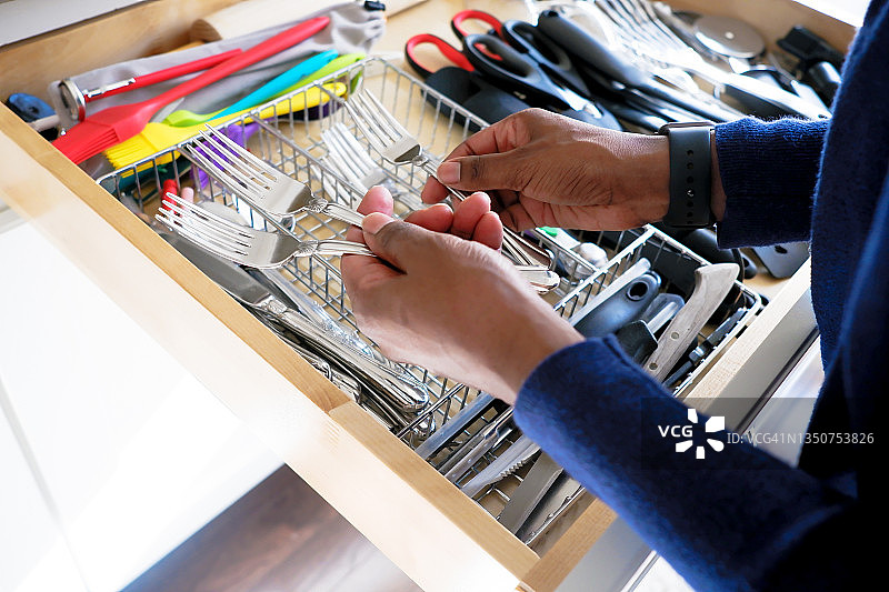 女人整理厨房抽屉里的叉子图片素材