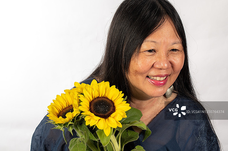 快乐的新加坡华人中年妇女手捧着一束向日葵图片素材