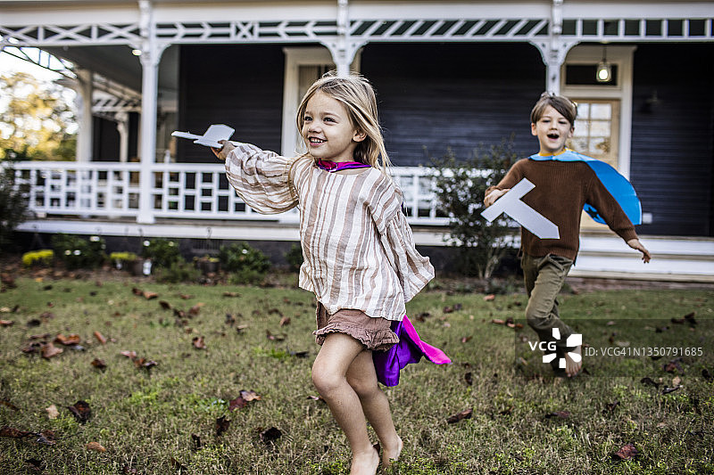 幼儿在农舍前玩纸板剑图片素材
