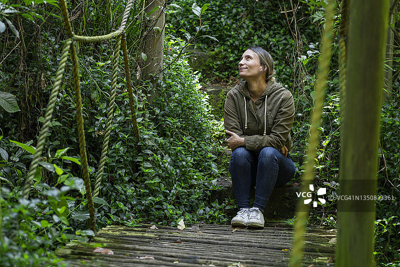 女人坐在森林里的吊桥上冥想图片素材