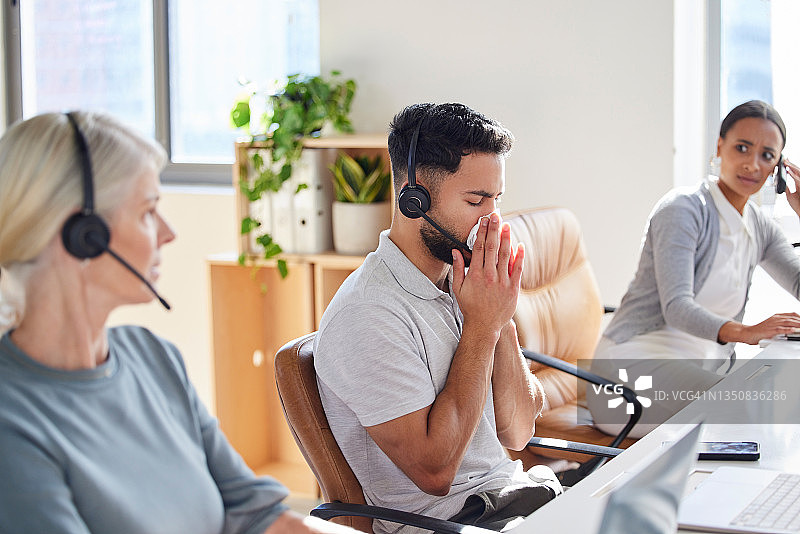 年轻商人与同事在呼叫中心工作时擤鼻子的镜头图片素材
