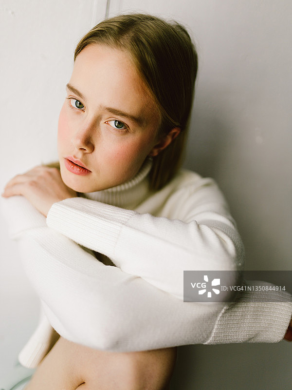 身穿白色毛衣的沉思年轻女子图片素材
