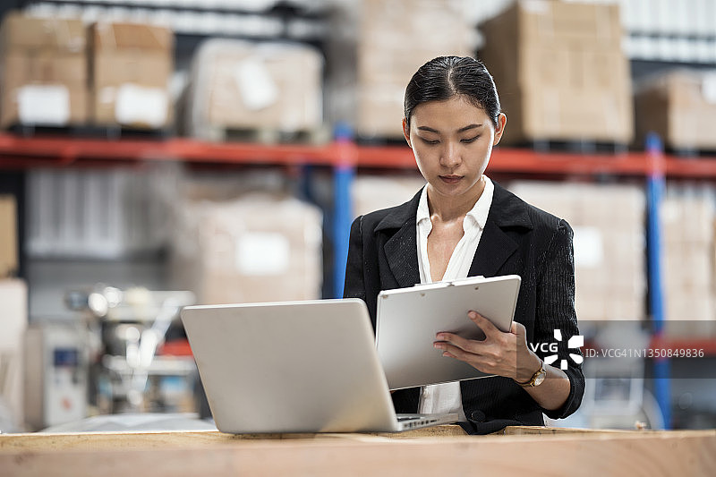 盘点配送仓库库存，女仓库经理核对库存清单，与ERP软件上的库存数据进行比较图片素材