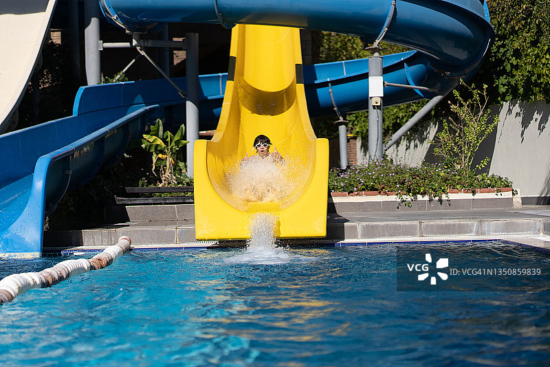 男孩在水上乐园玩滑梯图片素材