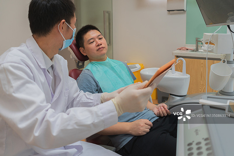 亚洲男医生使用平板电脑与病人交流图片素材