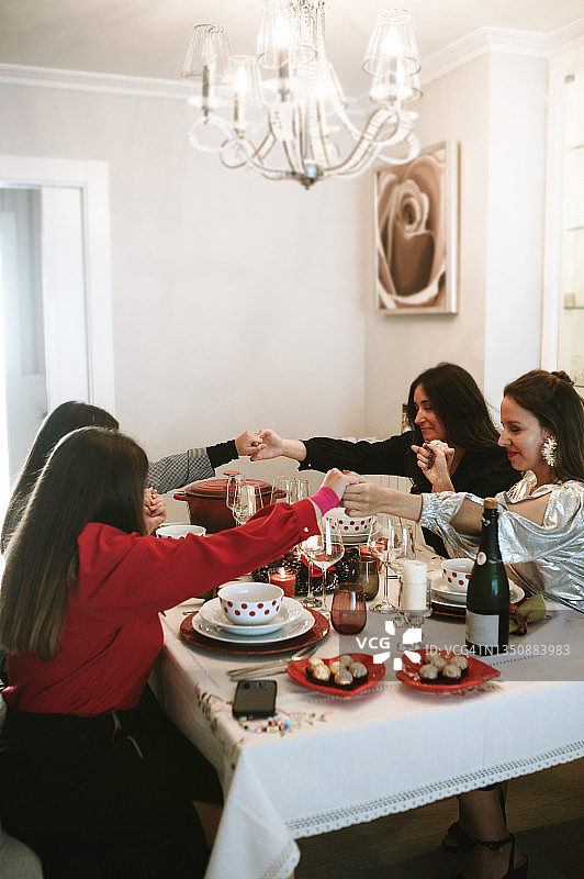 在庆祝晚宴上，四名女子手牵着手祈祷图片素材