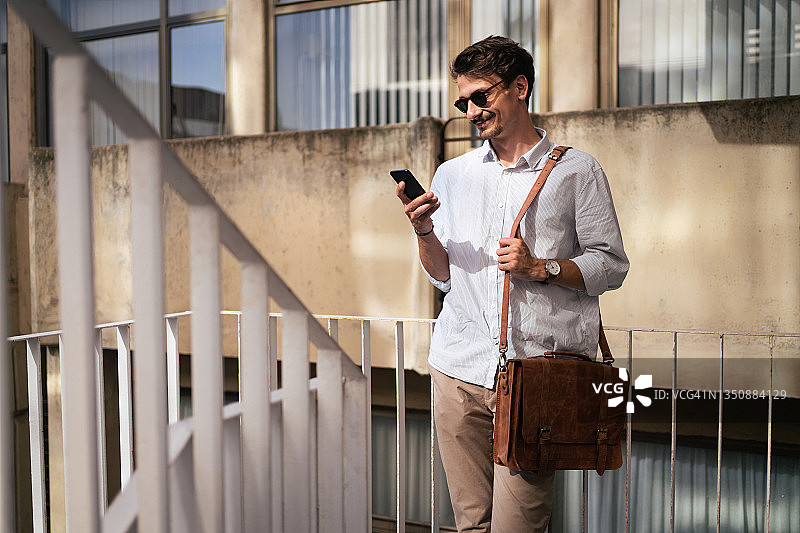 楼梯上使用手机上网的现代白人青年商人图片素材