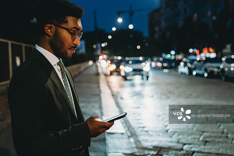 夜晚在城市里使用手机的年轻商务男士图片素材