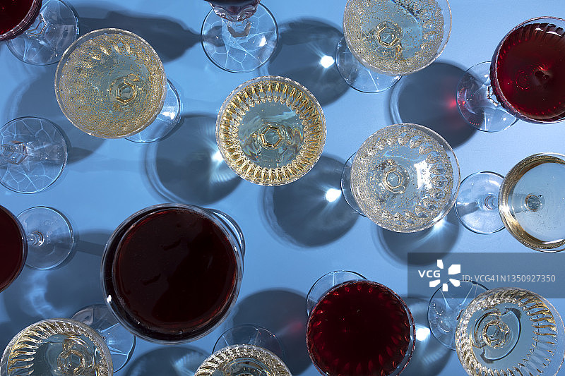 顶视图：蓝色背景上重复的香槟、红葡萄酒和白葡萄酒杯图片素材