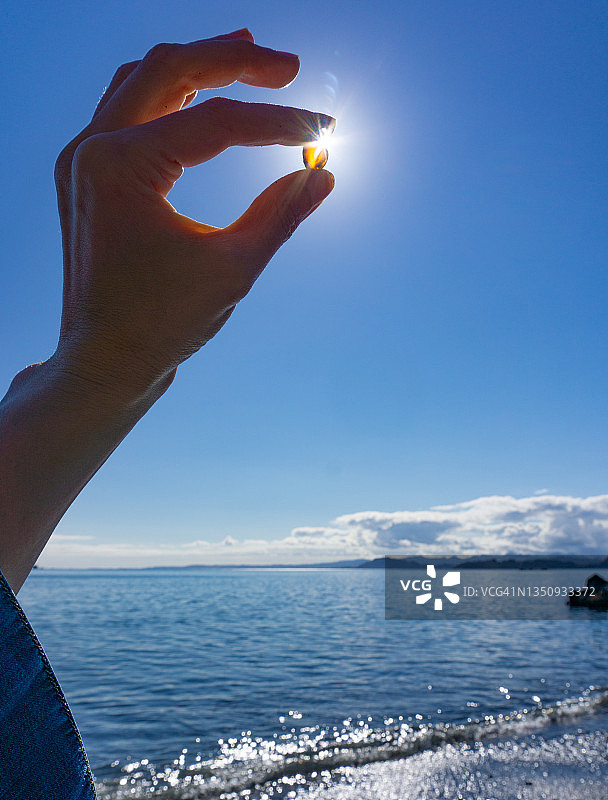 手持海玻璃，以太阳为背景图片素材