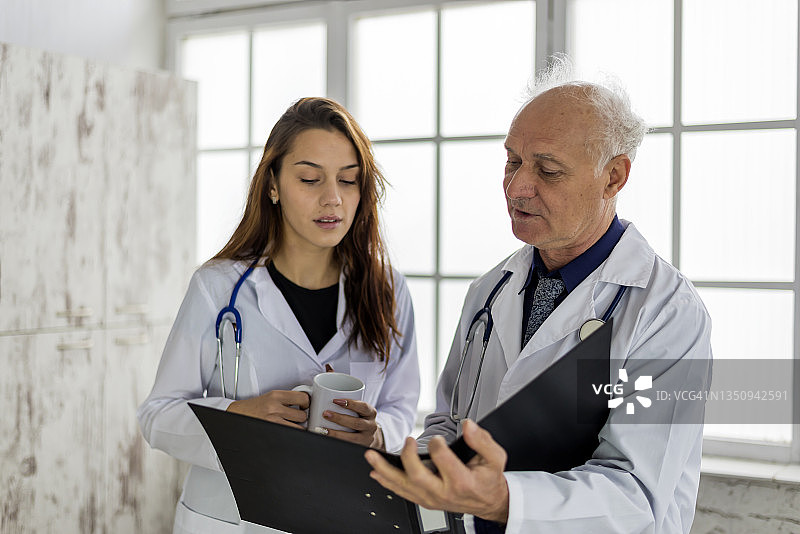 一位年长的男医生和一位年轻的女医生讨论即将进行的手术。图片素材