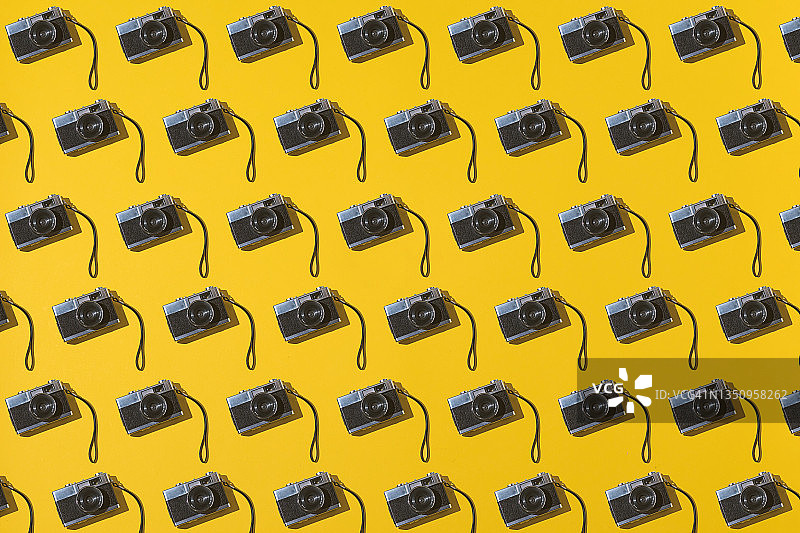 黄色背景上的35毫米模拟相机图案：复古摄影概念图片素材