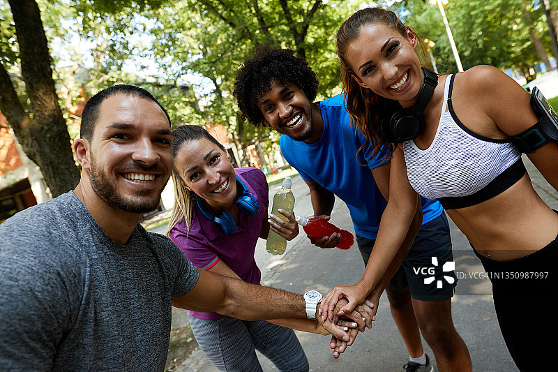 一群笑容满面的健身人士在户外叠手图片素材