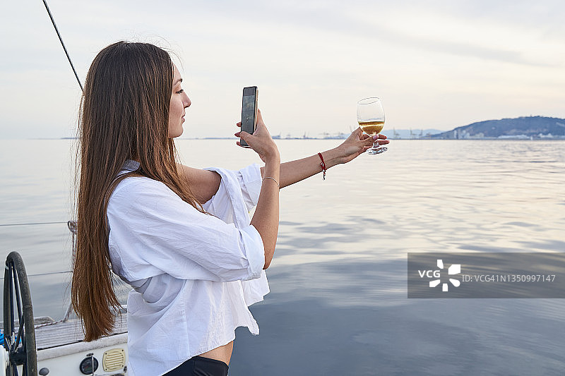 长发年轻人拍摄白葡萄酒杯图片素材