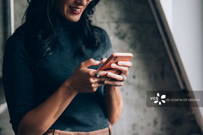 在办公室使用手机的匿名女职员图片素材