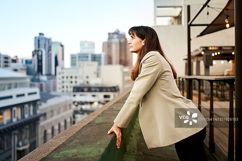 站在办公室阳台上看城市景观的女商人图片素材