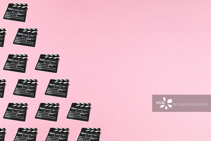 粉色背景上的旧木制电影场记板图案，左侧有复制空间，电影行业、电影、娱乐和好莱坞的概念图片素材