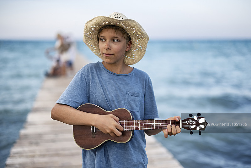在码头上弹尤克里里的青少年男孩图片素材