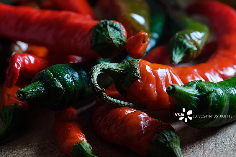 木制背景或厨房桌子上成熟和未成熟的红绿辣椒，有机农产品种植，美食烹饪香料图片素材