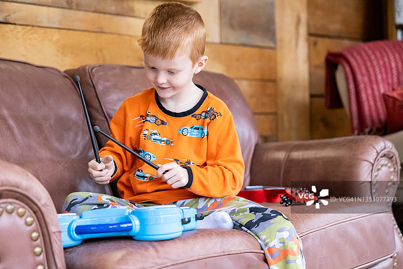 在客厅里打鼓的可爱红发男孩图片素材