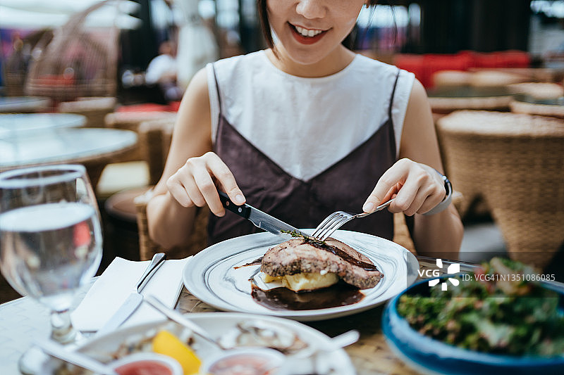 年轻亚洲女性在户外餐厅享用猪里脊和土豆泥图片素材