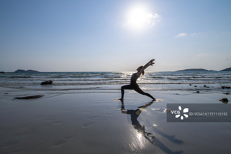 在海滩上练习瑜伽的年轻女人图片素材