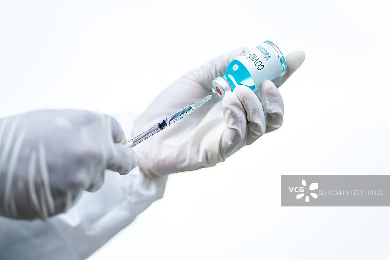 医生、护士、科学家、研究人员戴蓝色手套，手持流感、麻疹、冠状病毒、新冠疫苗，准备进行人体临床试验，疫苗注射、药物概念图片素材