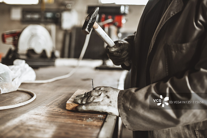 专心用锤子在木头上钉钉子的男性工人图片素材