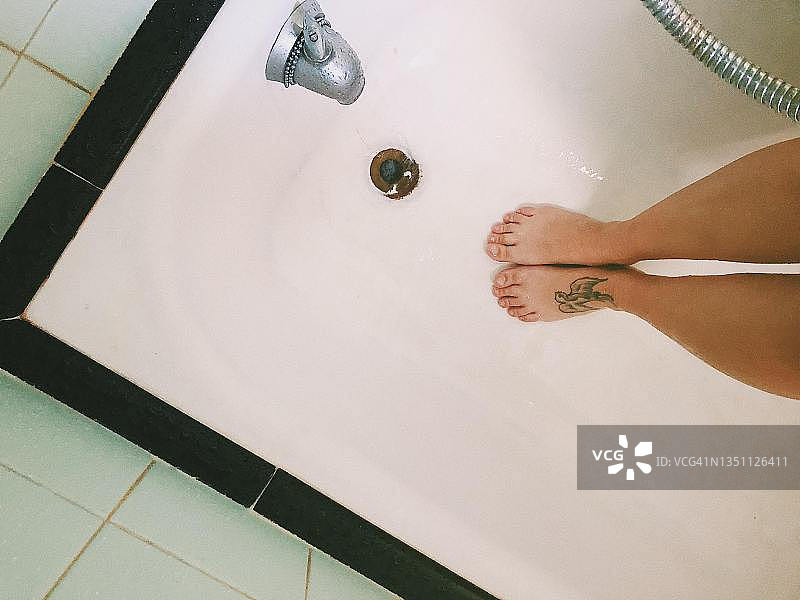 俯视：准备淋浴的浴缸和女人的脚图片素材