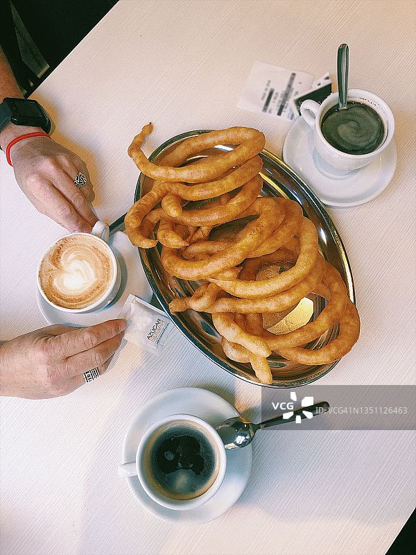 享用西班牙油条和咖啡的女人的俯视图图片素材