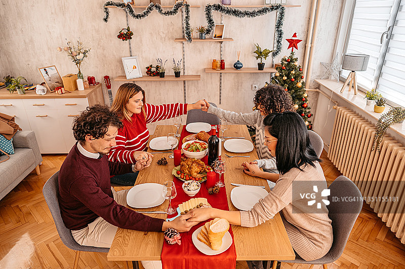 朋友们在节日晚餐前祈祷图片素材