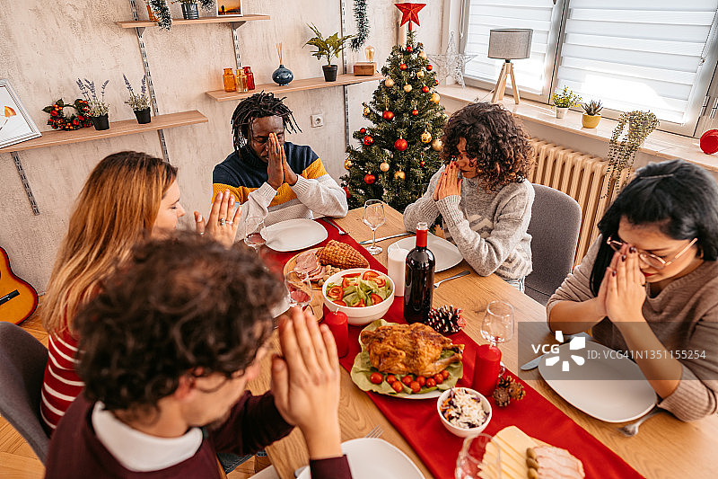 朋友们在节日晚餐前祈祷图片素材