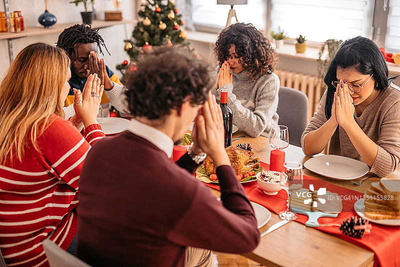 朋友们在节日晚餐前祈祷图片素材