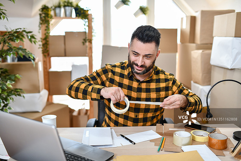 使用胶带完成包裹包装的现代快递员图片素材
