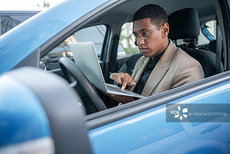 在二手蓝色汽车中工作的拉丁裔混血企业家肖像图片素材