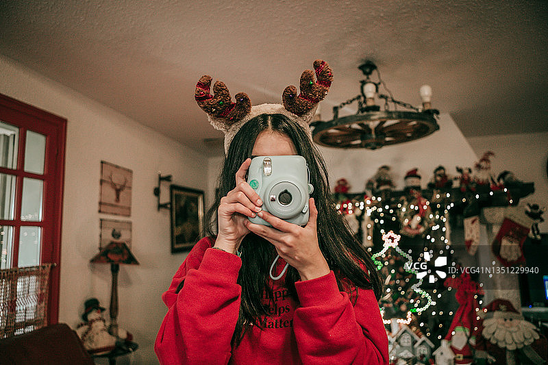 少女在圣诞节期间在家用一次成像相机拍照图片素材