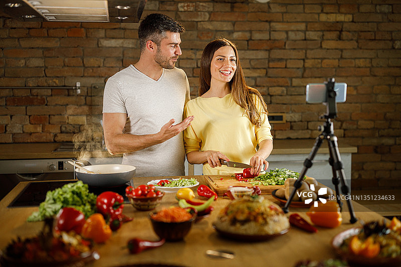 快乐夫妇在厨房制作健康餐时录制视频博客图片素材