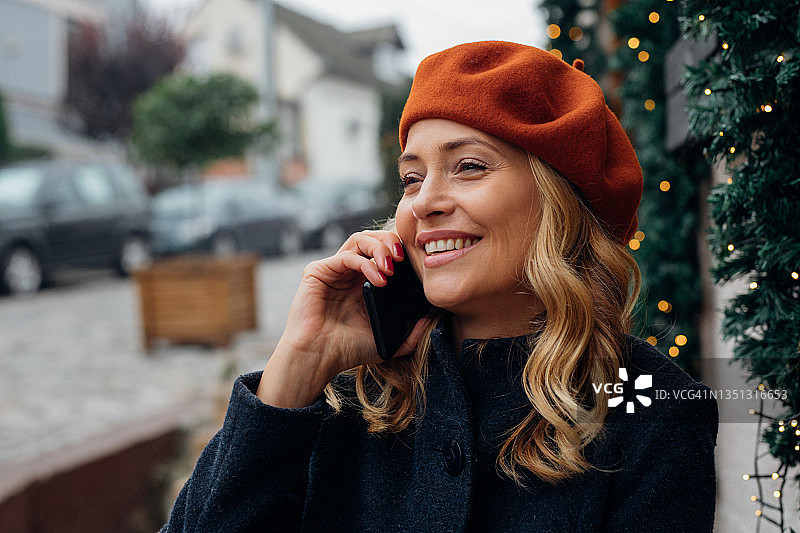 快乐的女人在户外咖啡馆里用手机聊天图片素材