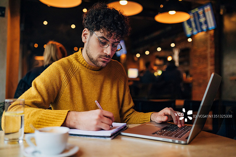 年轻学生在学院里上网课，在笔记本上写下重要的学习信息图片素材