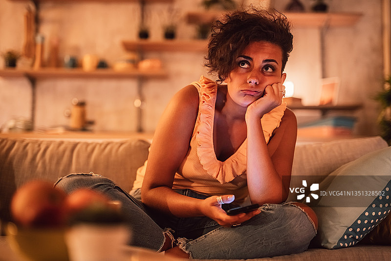 坐在沙发上玩手机的无聊女人图片素材