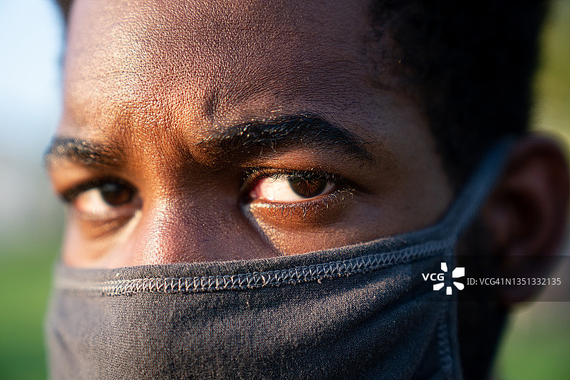 戴着黑色防护口罩的非洲裔男子特写，预防新冠病毒感染图片素材