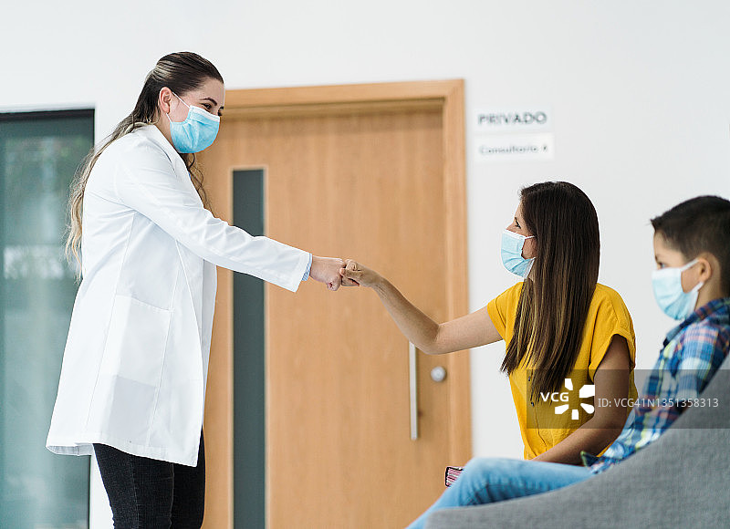 戴着口罩的女心理学家与病人（母亲）碰拳图片素材