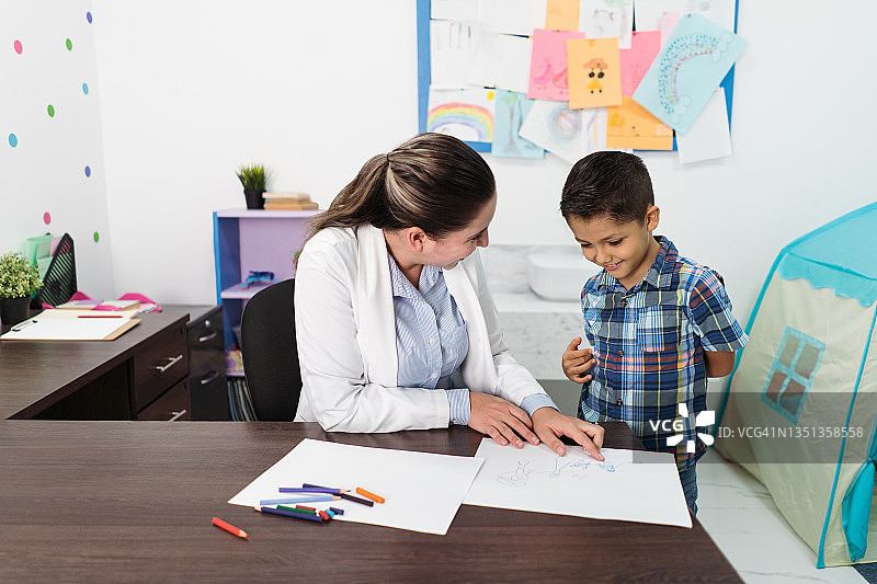 女心理咨询师看着男孩的画并进行指导图片素材