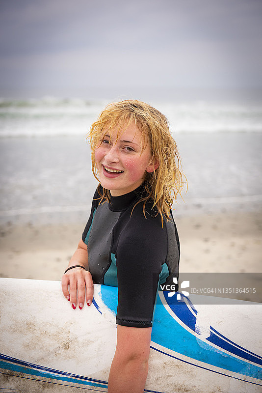 海滩上拿着冲浪板的健康少女图片素材