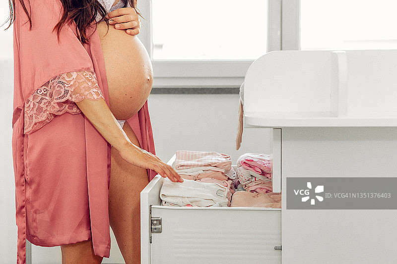 孕妇站在卧室的尿布台旁图片素材