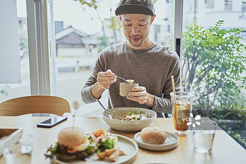 亚裔男子在素食咖啡馆享用午餐图片素材